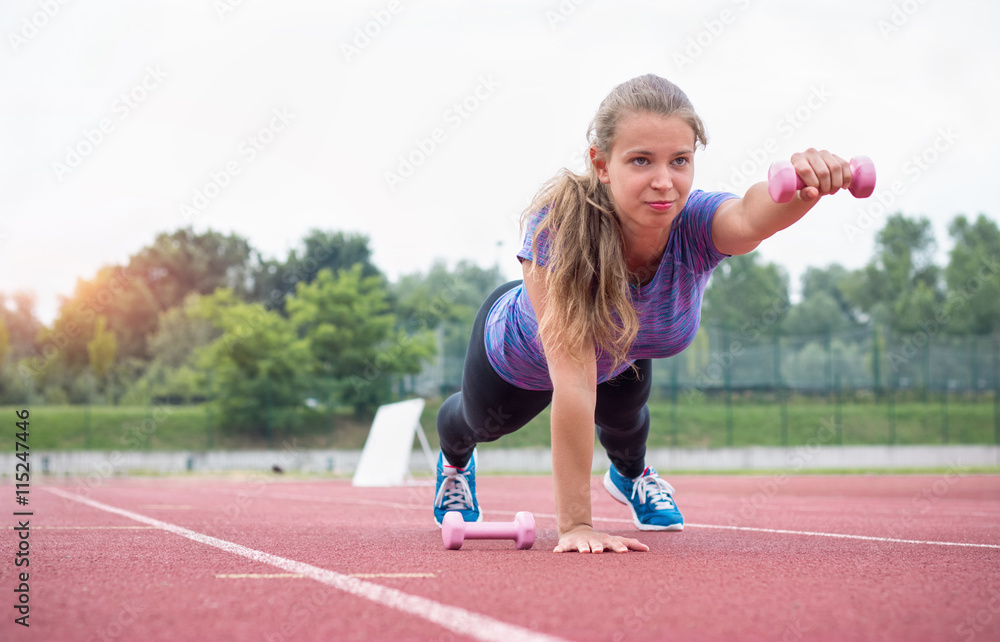 Young athletic woman exercising with dumbbells outdoors Young athletic woman exercising with dumbbells outdoors