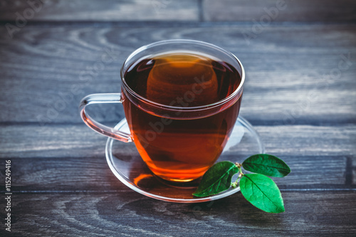 Toned photo. Color tone tuned. Glass cup of tea on wooden table background.