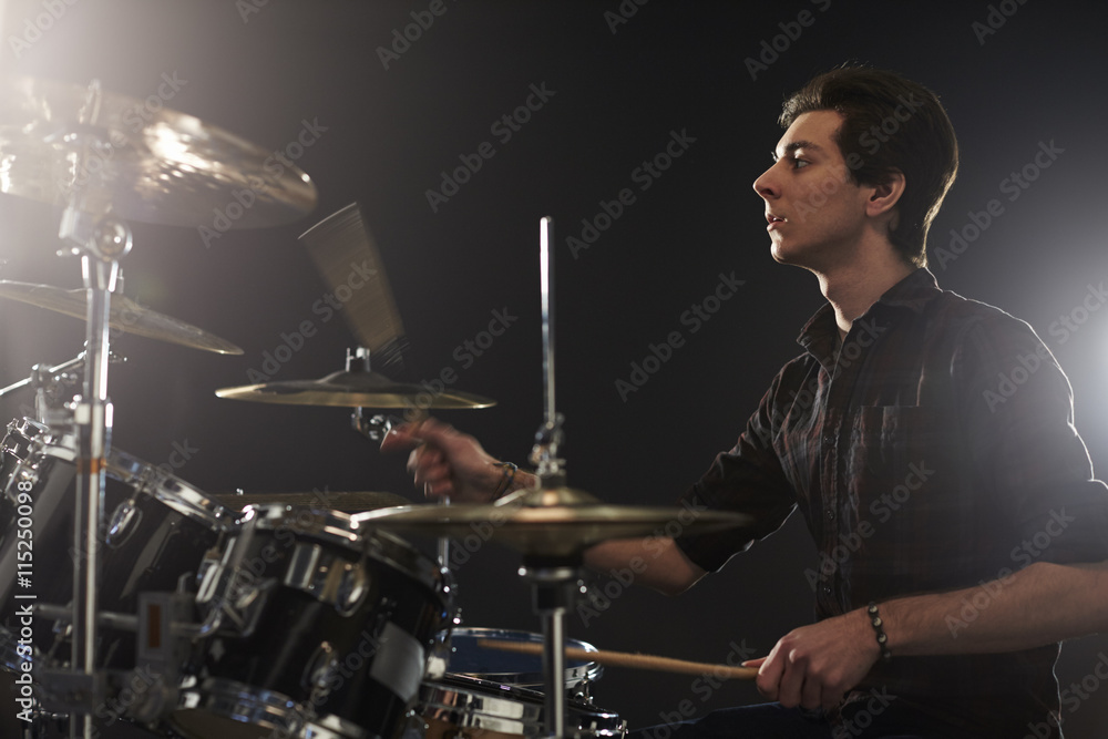 Naklejka premium Side View Of Young Drummer Playing Drum Kit In Studio
