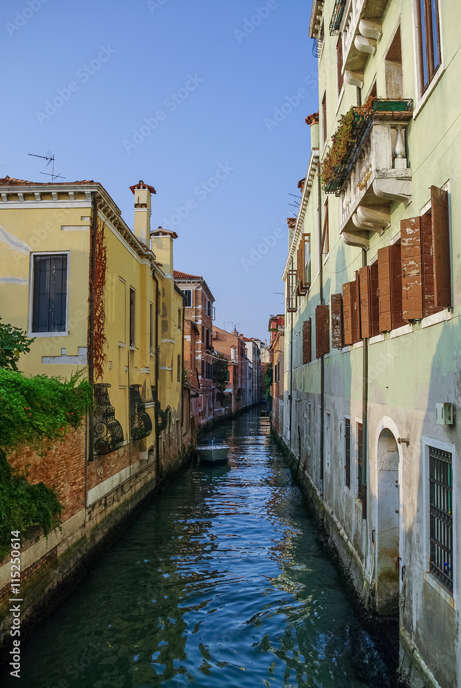 Narrow canal among old colorful brick houses in Venice, Italy