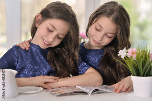 little twin girls reading a magazine