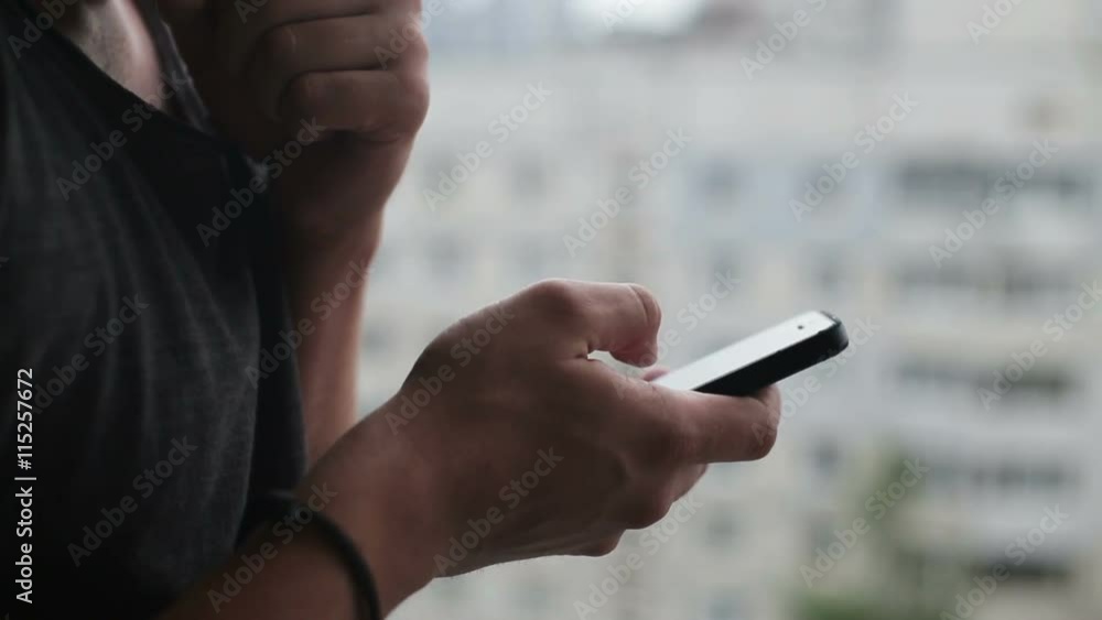 Young man drinking coffee and using smartphone on balcony Young man drinking coffee and using smartphone on balcony