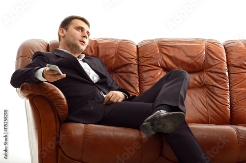 Tired businessman using phone .sitting on the sofa