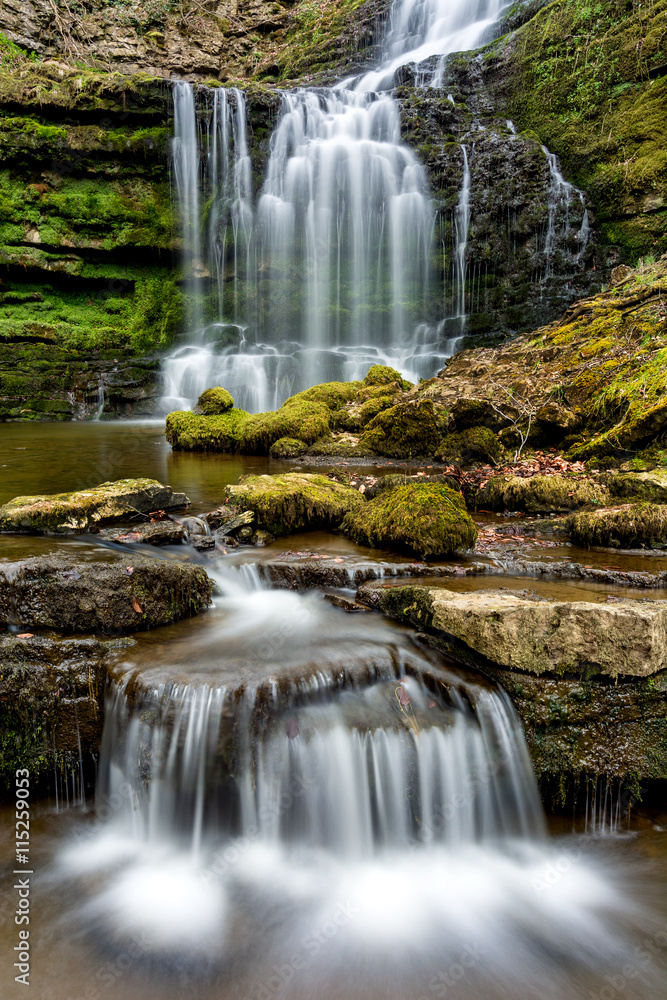 Obraz premium Flowing waterfall in remote Yorkshire woodland with small cascade. 