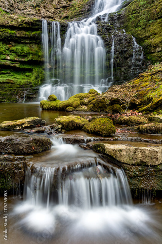 Flowing waterfall in remote Yorkshire woodland with small cascade. 