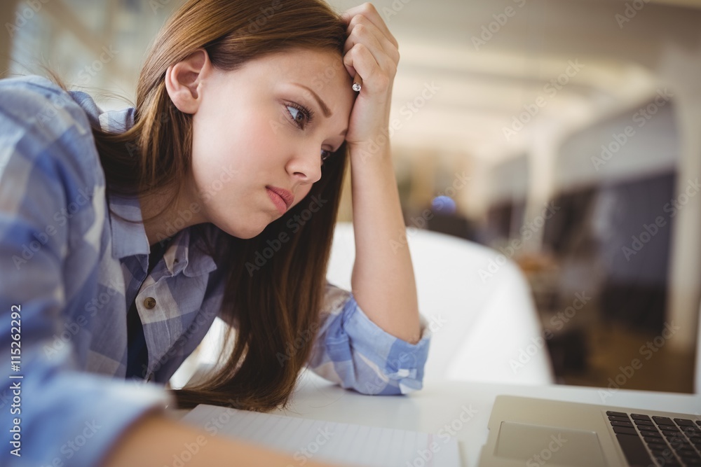 Stressed businesswoman with head in hand in office Stressed businesswoman with head in hand in office