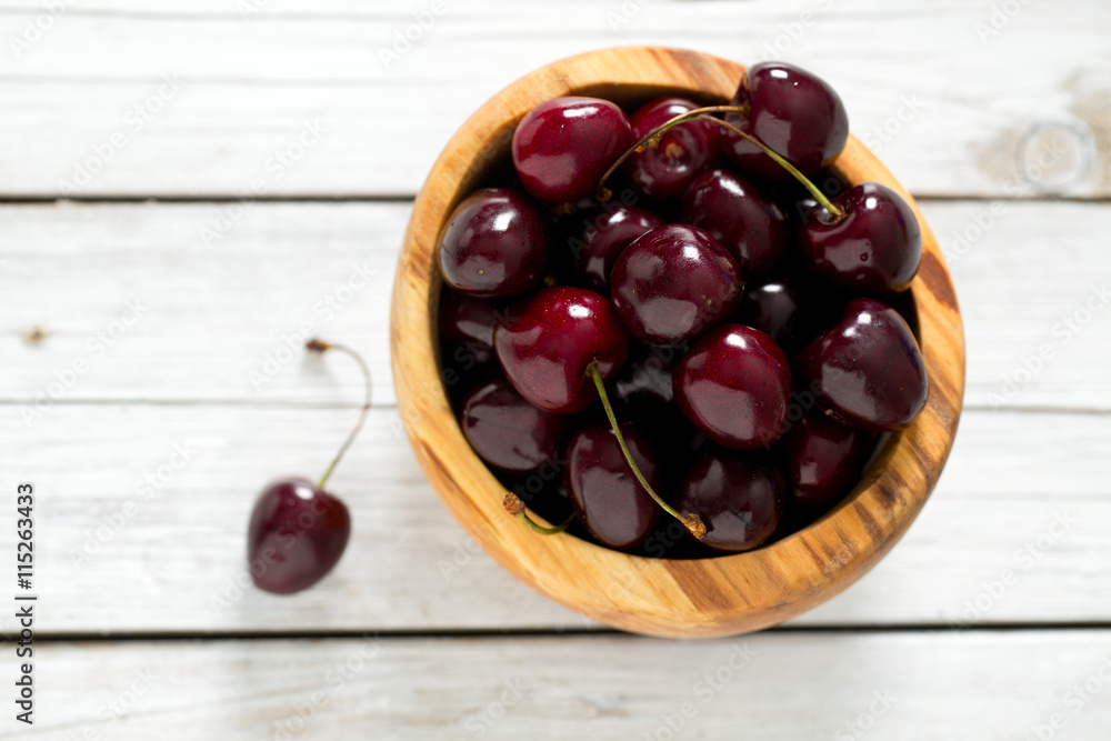 ripe red cherries on wooden surface