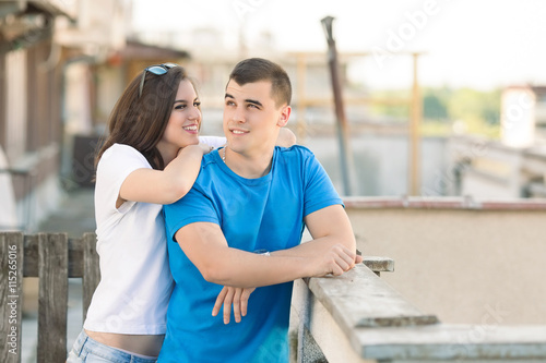 Portrait of happy teenage couple. Girl is leaning on the shoulder of her boyfriend and talking to him.