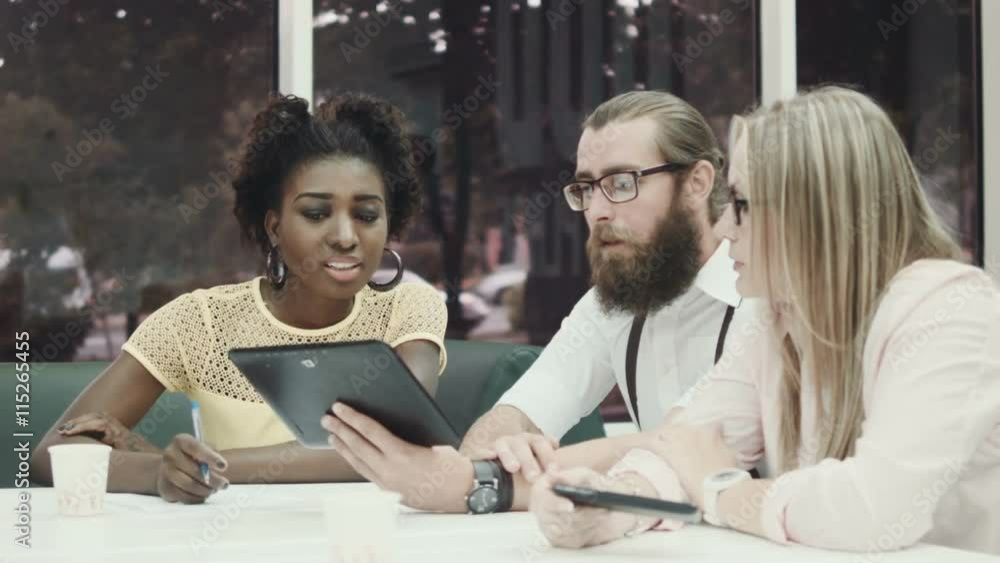 Afro-American woman and two caucasian colleagues using tablet in office Afro-American woman and two caucasian colleagues using tablet in office