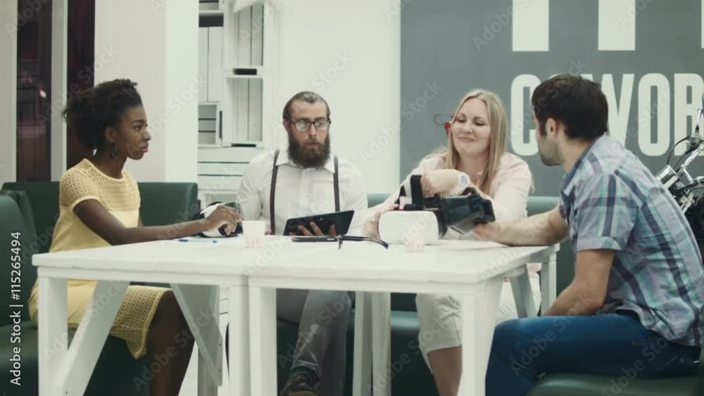 Bearded man with tablet looking at colleagues wearing virtual reality glasses