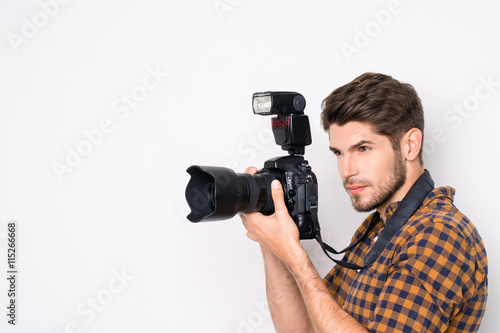Portrait of young handsome professional photographer taking phot