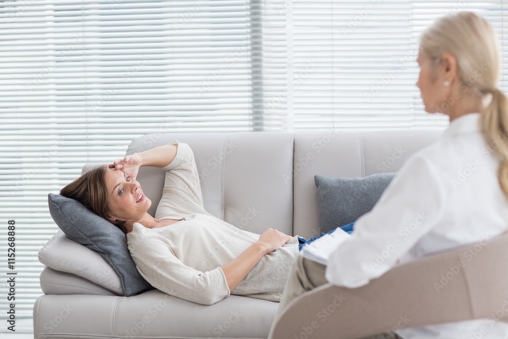 Woman lying on sofa talking to therapist Woman lying on sofa talking to therapist