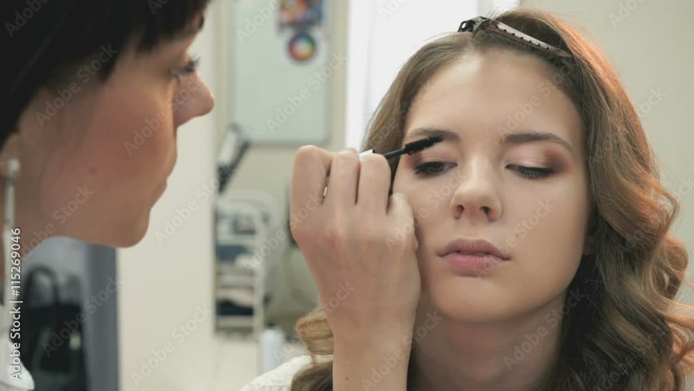 Makeup artist making make-up for a young model Makeup artist making make-up for a young model