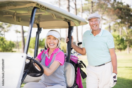 Smiling mature couple with woman sitting in golf buggy