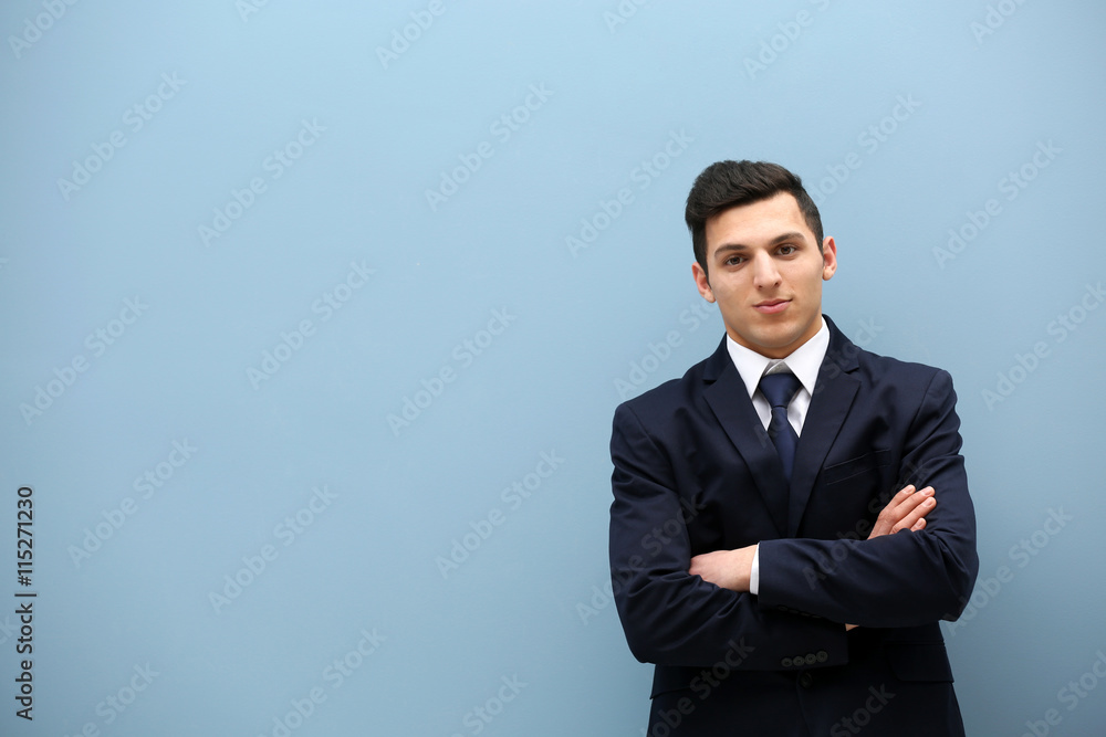 Attractive young man in a suit against light blue wall Attractive young man in a suit against light blue wall