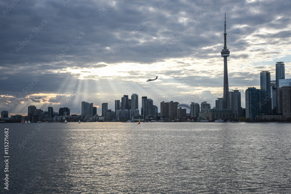 Obraz premium TORONTO SKYLINE WITH SUNBEAMS AND AIRPLANE IN THE DISTANCE