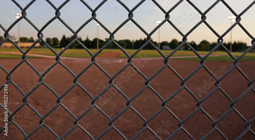 Photography A wide angle shot of a baseball field shot through a chain-link fence at dusk