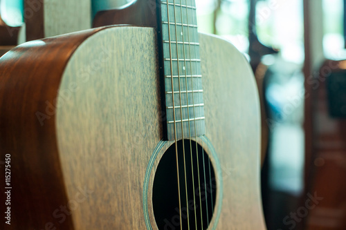 Close up of tuning peg on acoustic guitar headstock and many guitar in shop
