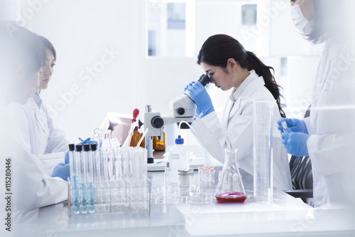 Foto Woman looking through a microscope in a laboratory
