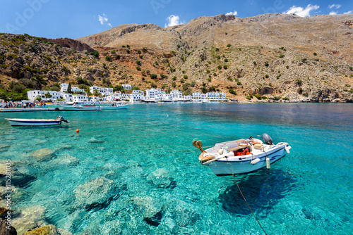 Mały motorboat przy jasną wody zatoką Loutro miasteczko na Crete wyspie, Grecja