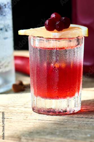 Boyarsky alcoholic cocktail consisting of vodka, homemade cranberry and Tabasco in a glass on wooden table closeup photo