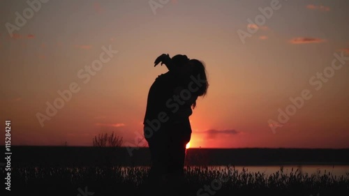 Silhouettes of young couple at sunset. Slow motion. photo