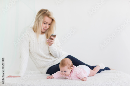 Young mother is holding a phone.