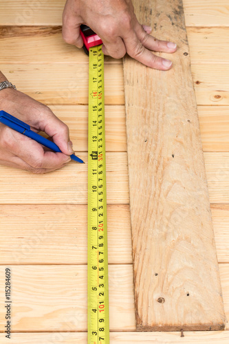 Male hands measuring wood flooring