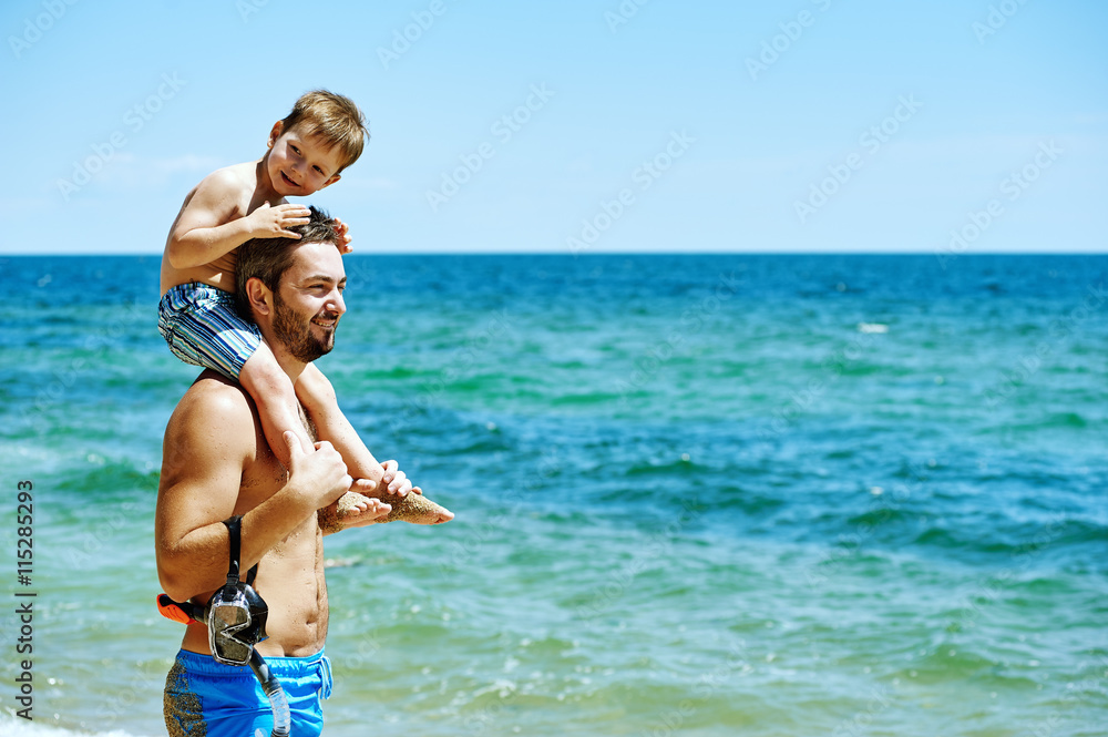 Father and son on the beach with underwater equipment . Father teaches son how to swim Father and son on the beach with underwater equipment . Father teaches son how to swim