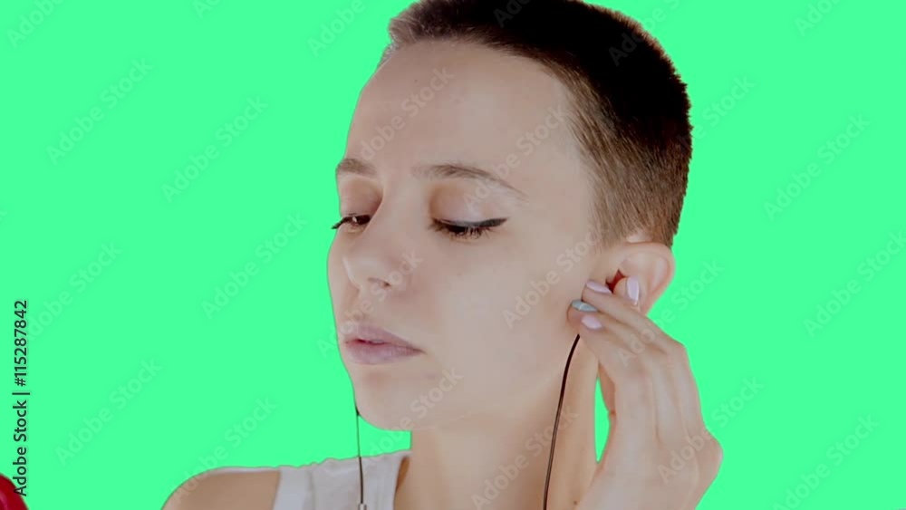 Beautiful bald girl, a girl with short hair brunette on the green screen, listening to music, mobile phone, headphones Beautiful bald girl, a girl with short hair brunette on the green screen, listening to music, mobile phone, headphones
