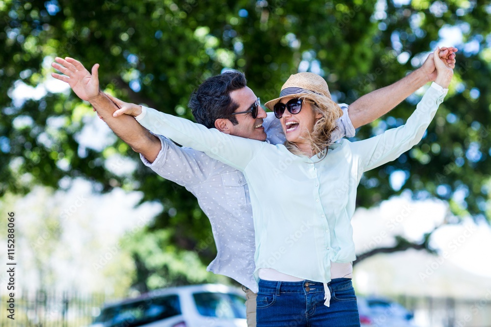 Obraz premium Couple with arms outstretched against trees