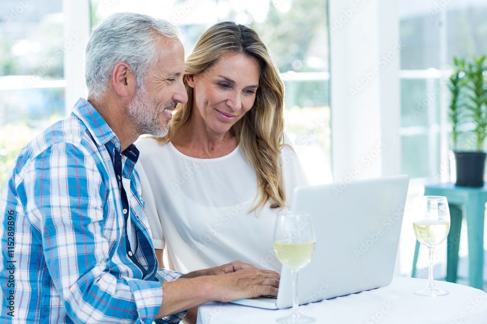 Couple looking in laptop on table Couple looking in laptop on table