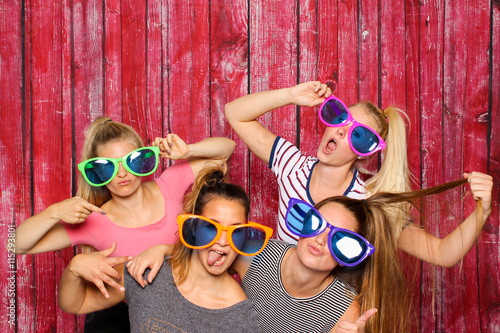 Mädchengruppe mit Brillen albern vor einer Fotobox - freche Mädchen mit Sonnenbrillen  photo