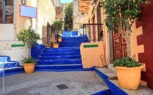 Fototapeta Naklejka Na Ścianę i Meble -  Ultramarine stairs with orange pots with trees. The picture taken in the town Symi, Greece 