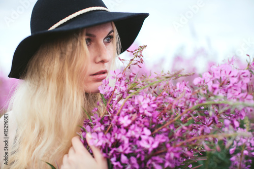 beautiful girl in black dress and hat standing in a field of lupine flowers © stock.film