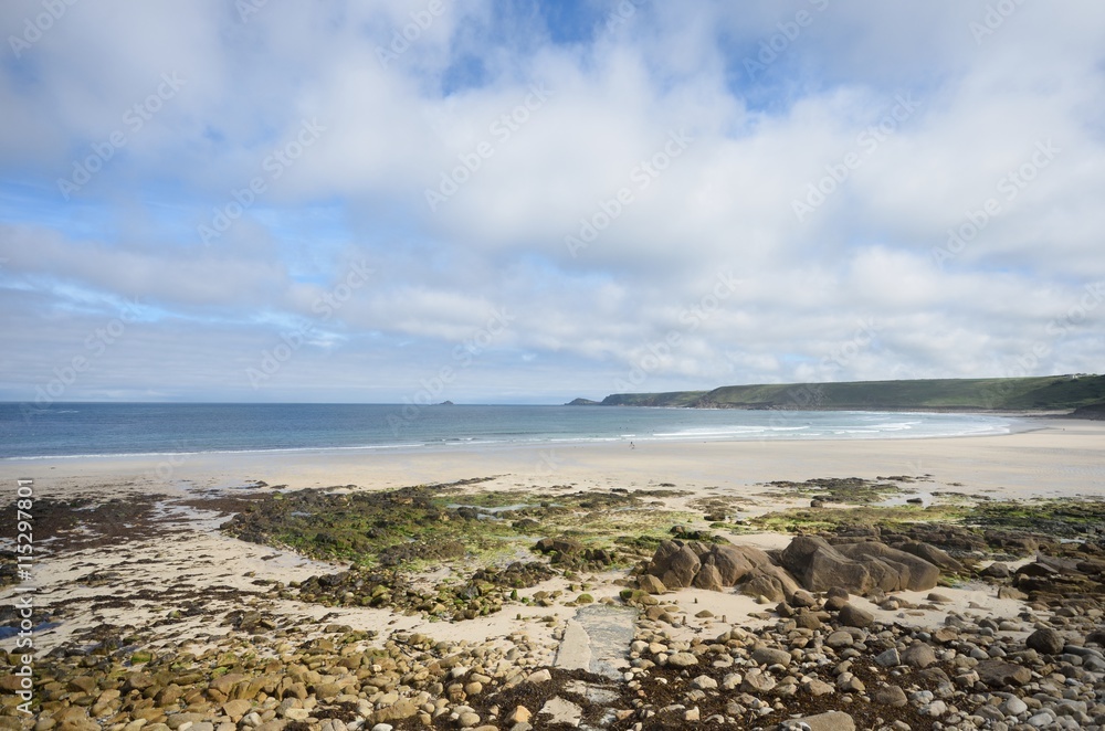 Empty Beach with stones in foreground and blue and cloudy skies