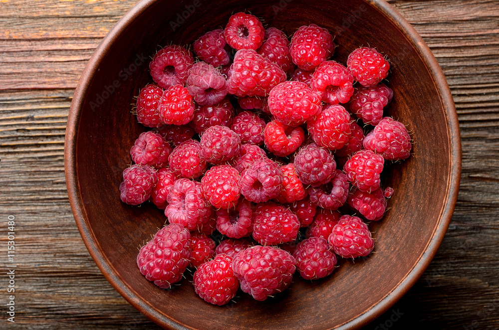 raspberries in a clay bowl on a wooden table raspberries in a clay bowl on a wooden table