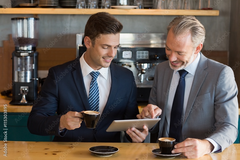 Businessmen using digital tablet in café