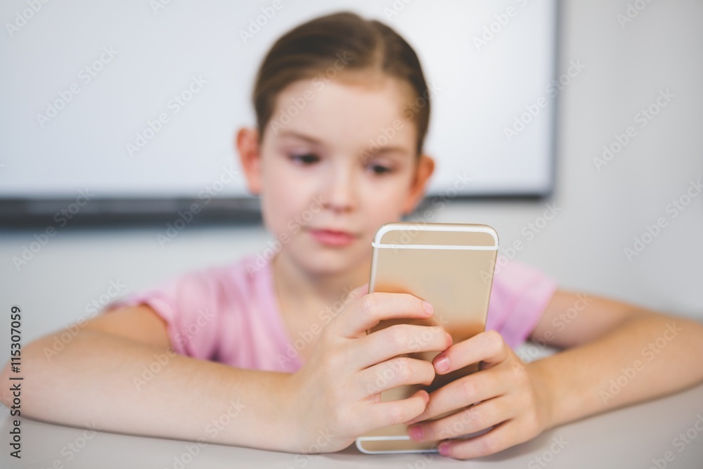 Schoolgirl using mobile phone in classroom Schoolgirl using mobile phone in classroom