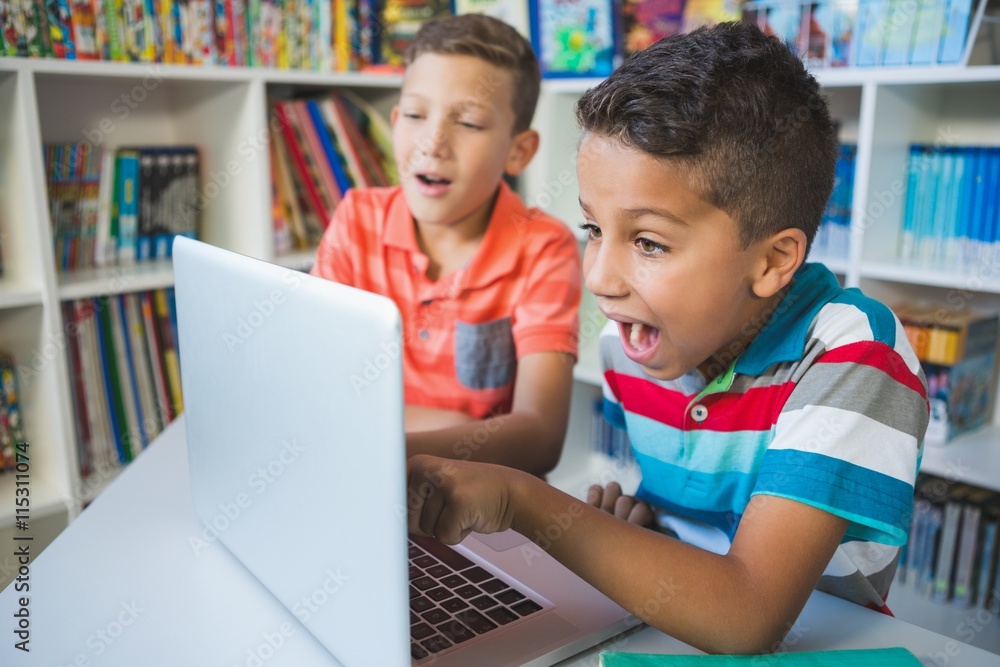 Schoolkids using laptop in library Schoolkids using laptop in library