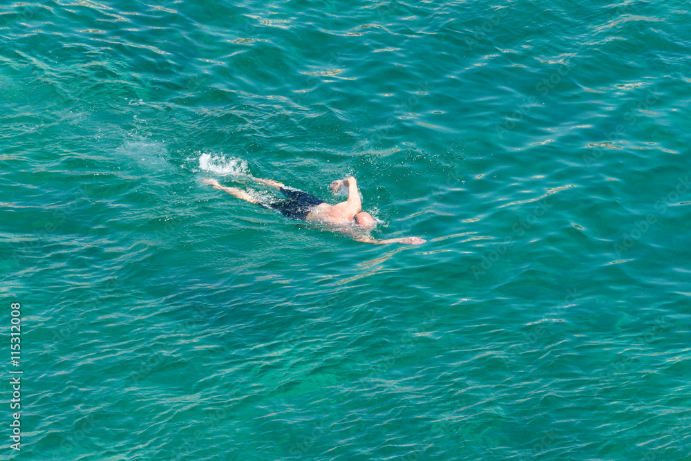 man swimming in a transparent sea water