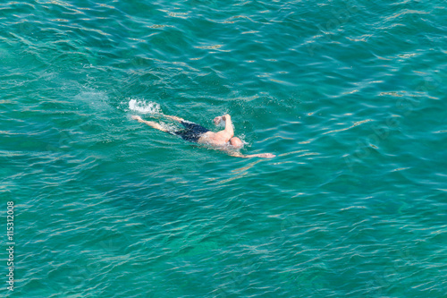man swimming in a transparent sea water