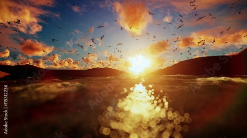 Lake surrounded by hills with seagulls flying against beautiful sunrise