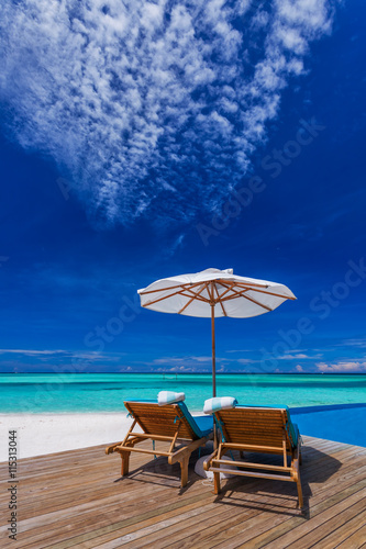Fototapeta Naklejka Na Ścianę i Meble -  Sun umbrellas and wooden beds on tropical beach with the best vi