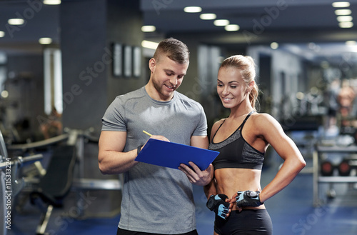 Fotografie smiling young woman with personal trainer in gym