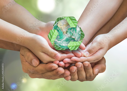 Fototapeta Naklejka Na Ścianę i Meble -  Parent guardian children hands holding together recycled green leaf arrow sign planet on blur nature greenery background sun flare Environment CSR ESG concept Element of this image furnished by NASA