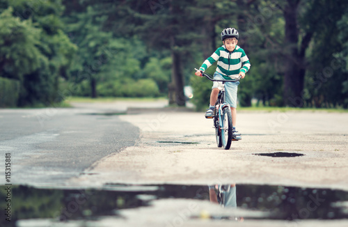 child on a bicycle at asphalt road in summer