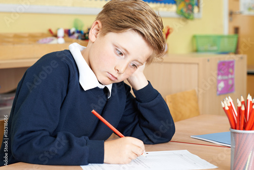 Fotografija Bored Male Elementary School Pupil At Desk