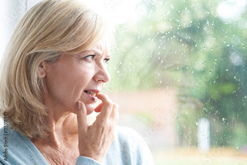 Sad Mature Woman Suffering From Agoraphobia Looking Out Of Windo photo