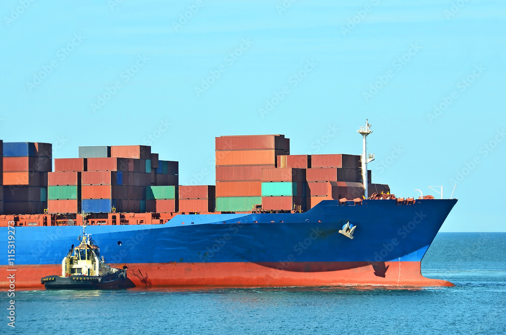 Fototapeta premium Tugboat assisting container cargo ship